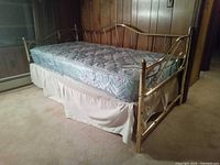 Brass daybed frame with mattress and dust ruffle, side view
