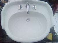 Top view of white oval pedestal sink basin with faucet and drain