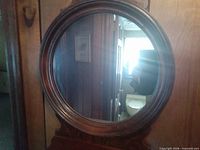 Front view of wood-framed oval mirror with shelf