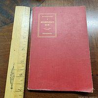 Front cover of red cloth hardcover with ruler for scale