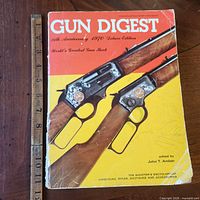 Front cover of Gun Digest showing title, rifles, pen scribble, ruler indicating 11.5 in.