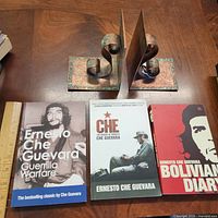 Front view of three paperback books flanked by metal scroll bookends