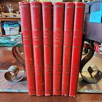 Spine view of six red cloth Ellery Queen books in holder