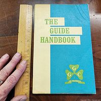 Front cover beside ruler showing title and emblem