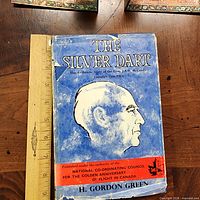 Front cover of The Silver Dart book with ruler for scale, showing worn dust jacket