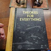 Front cover of book alongside ruler showing approx 11-inch height, visible water-stain spots