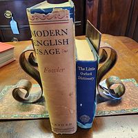 Two dictionaries standing between bookends showing spines and dust jacket wear