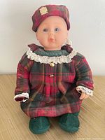 Front view of Anne Geddes Scottish doll seated, full outfit visible