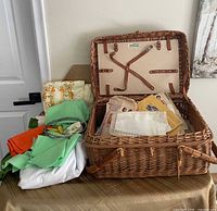 Overall view of open wicker basket, visible sewing patterns and folded fabric pieces beside basket