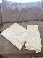 Folded linen and crochet tablecloths on sofa