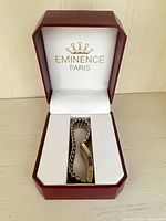 Bracelet inside open red Eminence Paris box showing logo and gold-tone link design