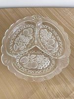 Top view showing three sections, etched fruit designs, scalloped edge