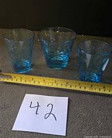 Three aquamarine blue polka dot glasses side by side with tape for scale