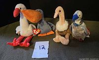 Group shot of four Ty Beanie Babies birds standing side by side with paper marker 12