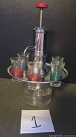 Full view of chrome and glass dispenser with all six shot glasses in tray