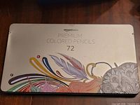 Front of silver metal tin marked AmazonBasics Premium Colored Pencils 72