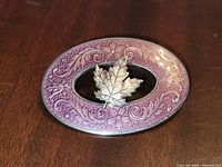 Front of sterling maple leaf brooch showing purple enamel border and maple leaf centre