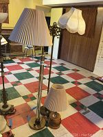 Three lamps displayed on a checkered floor with yellow walls and wood paneling; view shows all lamps fully assembled with shades.