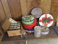 Assortment on table showing various tins and jars including holiday cookie tins and spice containers.