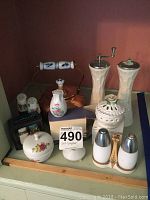 Photo showing tea kettle with ceramic handle, multiple salt and pepper shakers of ceramic and metal tops with floral designs, Lenox grinder.