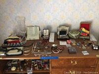Overview of the costume jewelry lot spread on wooden table with various jewelry pieces and containers
