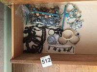 Top-down view of wooden and stone bead necklaces along with several bracelets and charm bracelets arranged in an open wooden drawer.