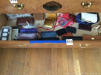 Drawer with over 10 assorted wallets, change purses, and small frames in various colors and materials