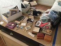 Full lot overview showing men's watches, tie clips, pins, boxes, belts, and a decorative tin.