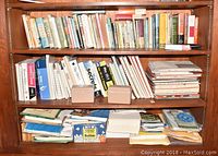 Shelves filled with assorted books including technical manuals, paperbacks, and reference volumes with some stacked horizontally on the bottom shelf.