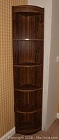 Full view of one dark wood grain corner cabinet showing all five shelves and triangular shape suitable for corner placement.