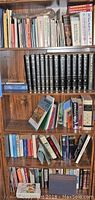 Wooden bookshelf filled with multiple assorted books including encyclopedia set, personal finance and memoir titles.