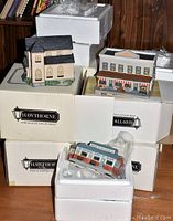 Overview of multiple boxed Hawthorne Porchlight Collection house models stacked showing original packaging and three distinct miniature buildings wrapped and displayed