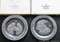 Two Morgantown Crystal plates with nativity scenes and original boxes visible, placed side by side on a wooden surface.