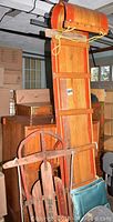 Full view of wooden toboggan sled with straight and curved wood panels, metal runners, and attached yellow rope.