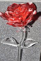 Close-up of red crystal rose flower and clear crystal stem with leaves in original foam-lined box.