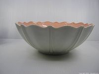 Side view of scalloped white exterior with pink interior rim visible