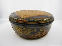 Side view of closed round bamboo basket showing lacquered decoration