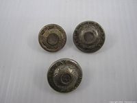 Front view of three buttons showing design and wear