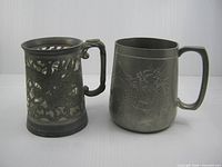 Both pewter mugs side by side showing differing designs
