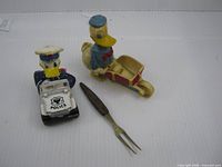 All three items laid out: police jeep toy, wooden scooter toy, two-prong fork