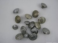 Group shot of all 16 firefighter uniform buttons showing variety of sizes and finishes