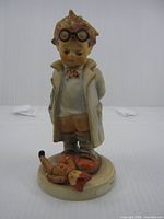 Front view of figurine showing boy doctor with doll on base