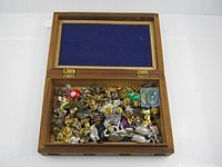 overall view of open carved wooden box filled with lapel pins