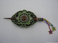 Full view assembled barrette with stick inserted, showing beads and tassels