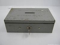 Front view of grey metal bank with key in lock