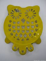 Front view of yellow enamel cast metal owl trivet