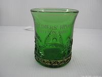 Front view of green souvenir tumbler showing decorative pattern and lettering