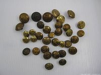 Overview of all 35 vintage brass military buttons spread on white background
