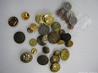 Group shot of all 34 metal uniform buttons in assorted sizes and finishes
