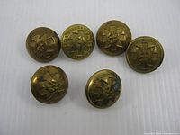 Front view of six brass buttons showing crest details